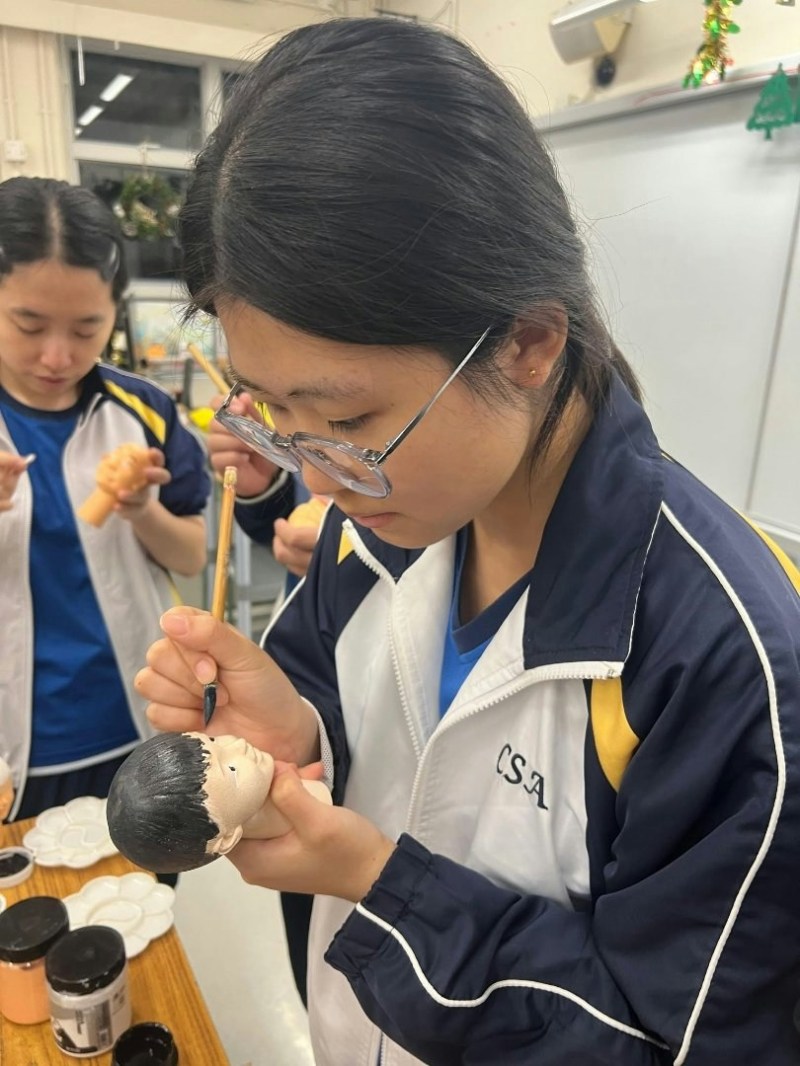 同学亲手为木偶素胚上色。