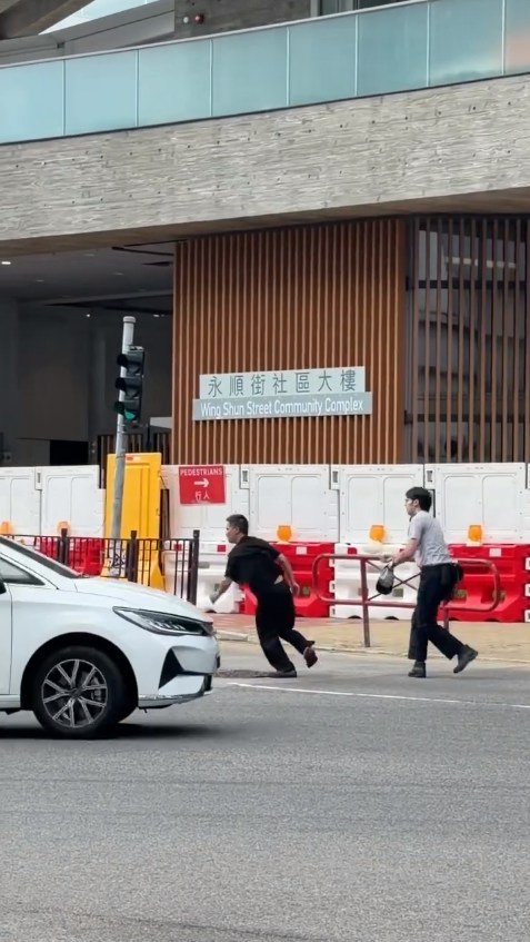 黑衫男情绪激动极力抗拒,最终挣脱执法人员,并迅速跑走。