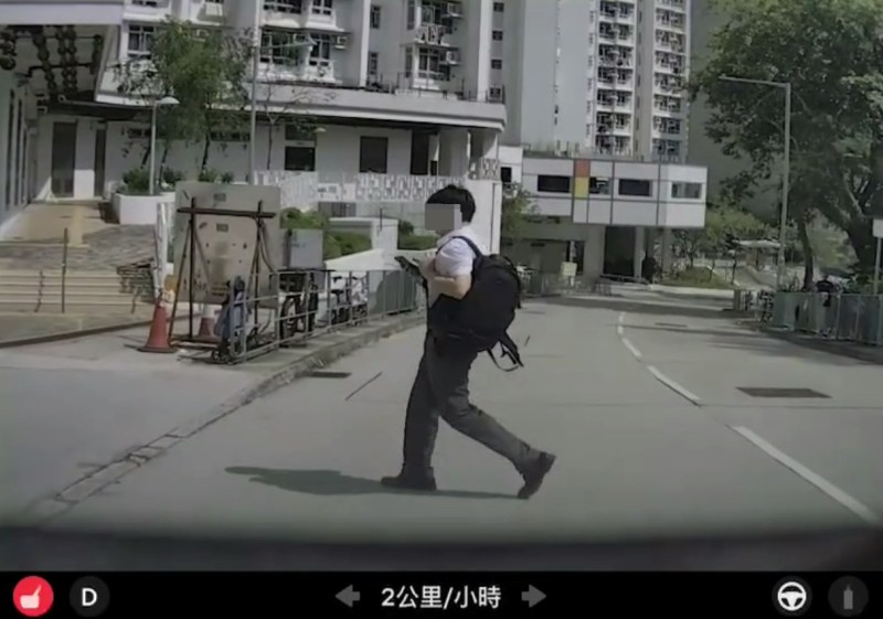 画面清楚可见,该名男生右手持着一部智能电话,双眼一直盯着手机,由踏出马路至行至片主车头中央,全程未曾抬头张望两旁路面状况。