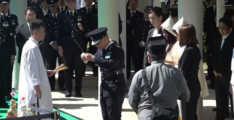 周一鸣与其他警队同袍轮流在墓前上香拜祭。