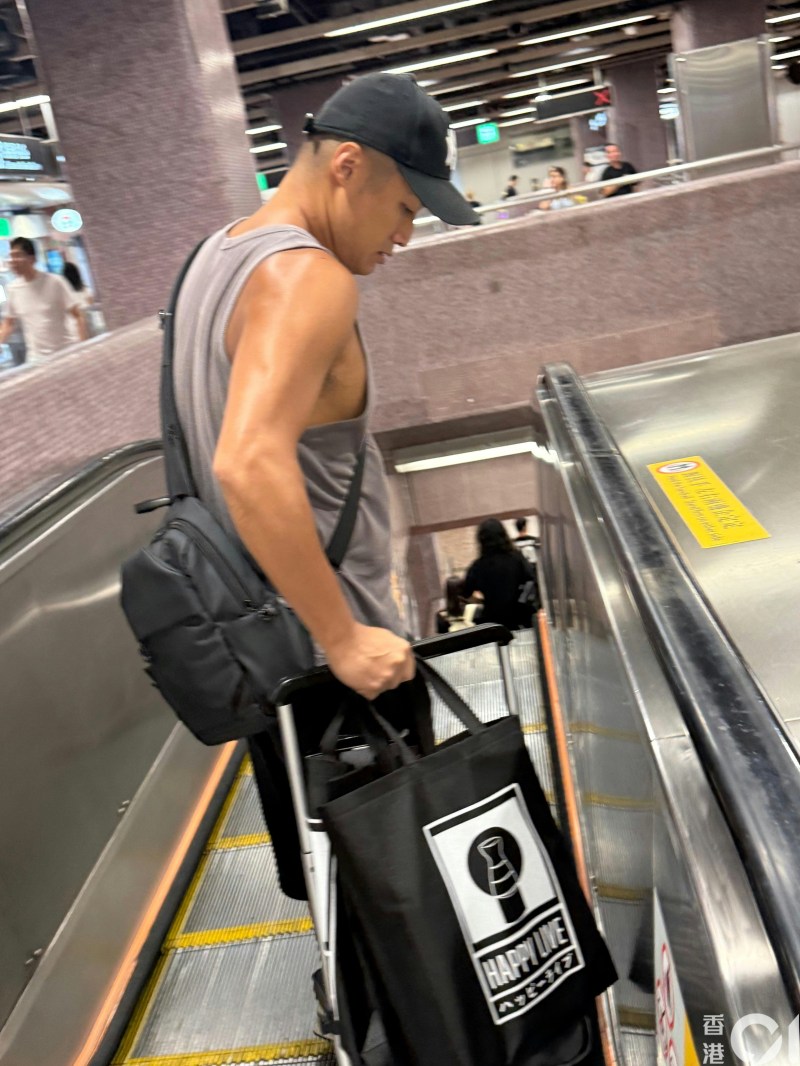 翟威廉身穿灰色工字背心乘搭扶手電梯,結實手臂極之搶眼。