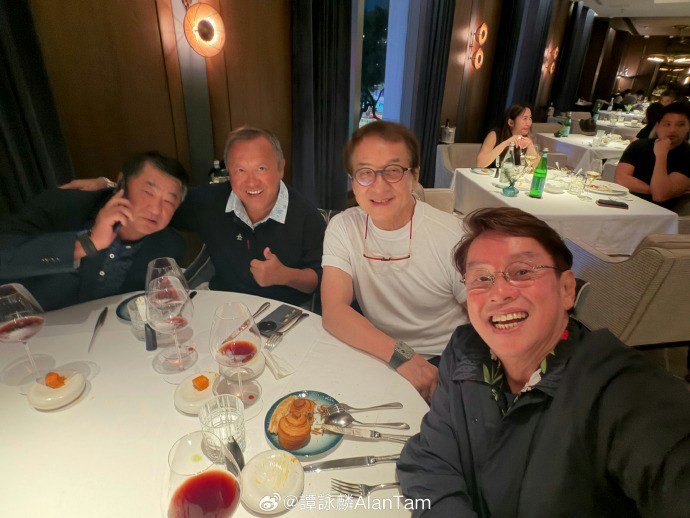 大哥成龙穿着简约白T配眼镜,与多年好友碰杯畅谈,极具亲和力。(微博照片)